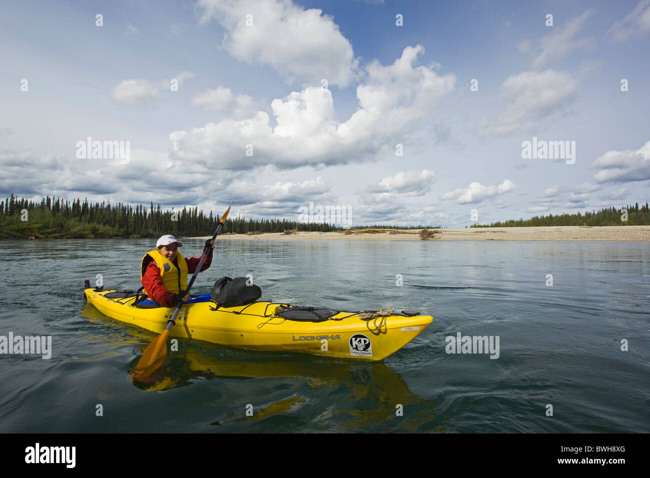 Giovane donna in kayak o canoa, kayak, ampio paesaggio aperto, superiore Liard River, Yukon Territory, Canada Foto Stock