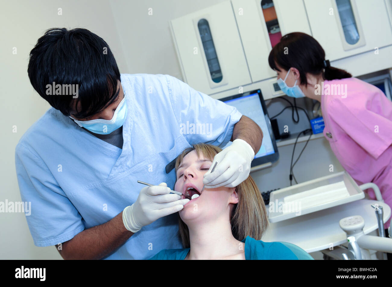 Paziente femmina ad una chirurgia dentale avente denti a controllare da un maschio di dentista asiatica Foto Stock