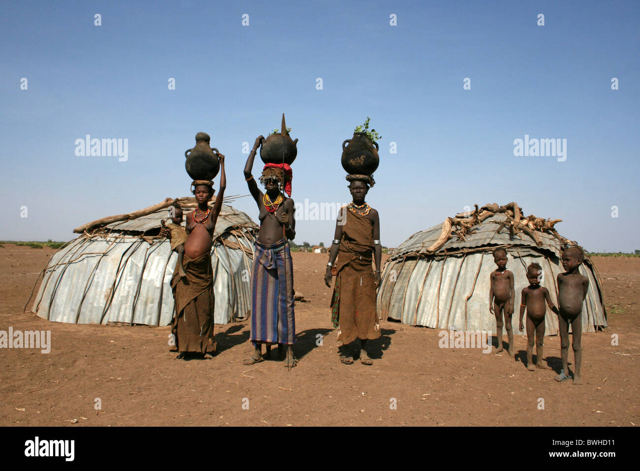 Dassanech Tribeswomen e bambini in piedi al di fuori della loro capanne, Omorate, Valle dell'Omo, Etiopia Foto Stock