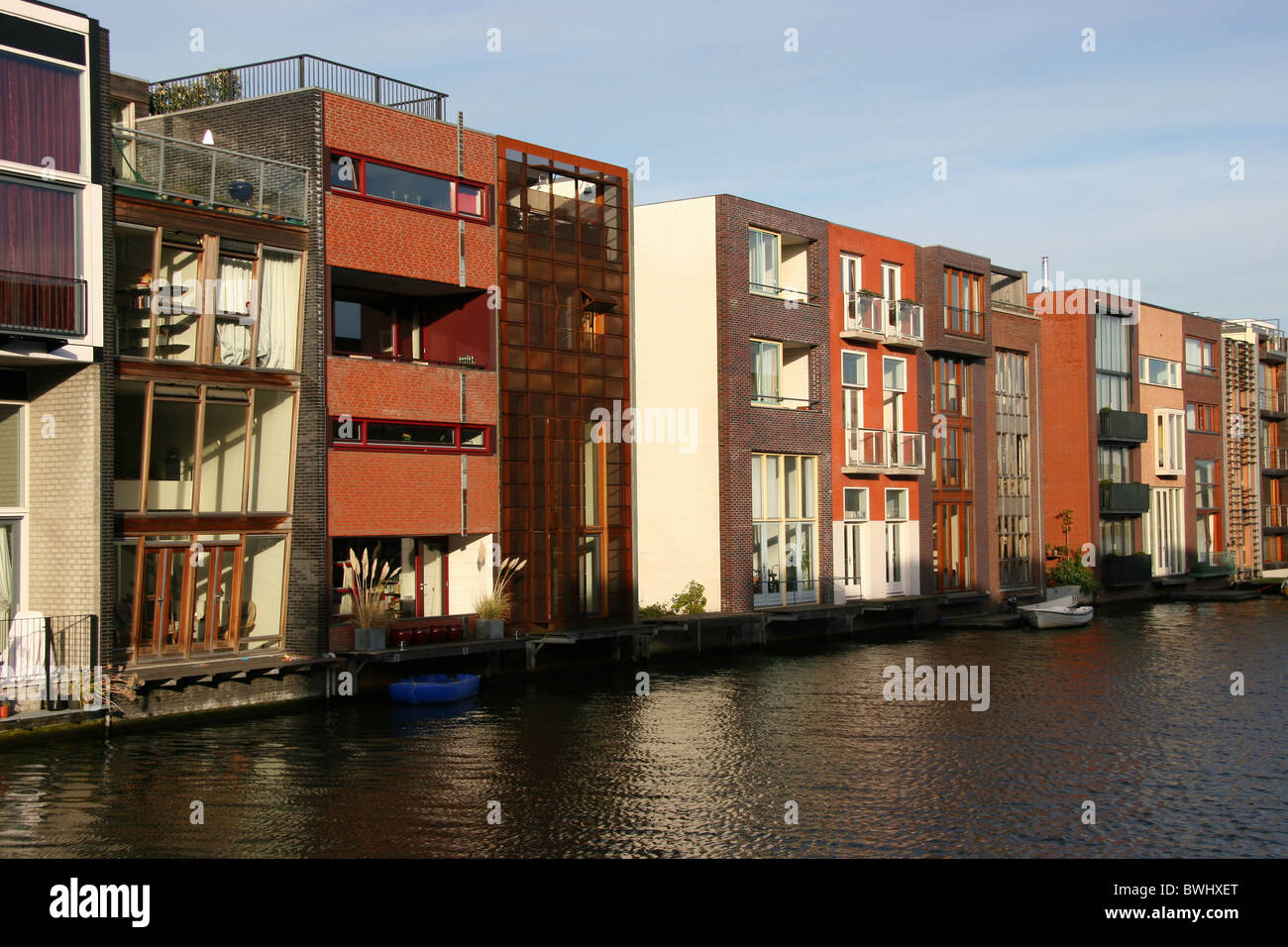 Holland Olanda Holland Europa Amsterdam fila di case moderna architettura moderna Gracht canal acqua ca Foto Stock