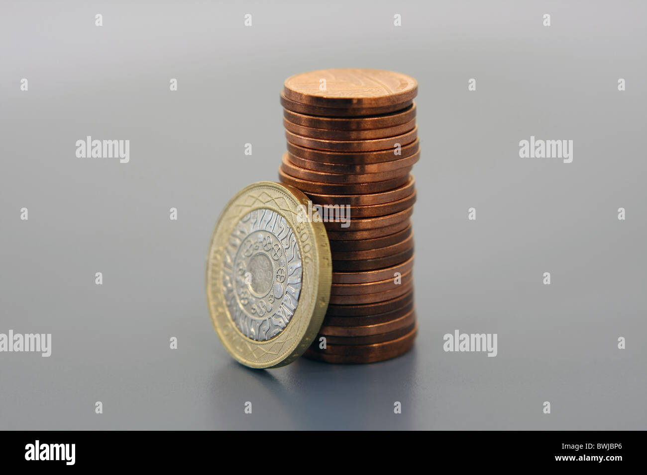 Una sterlina GBP 2 moneta in appoggio contro una pila di 1 monete Foto Stock