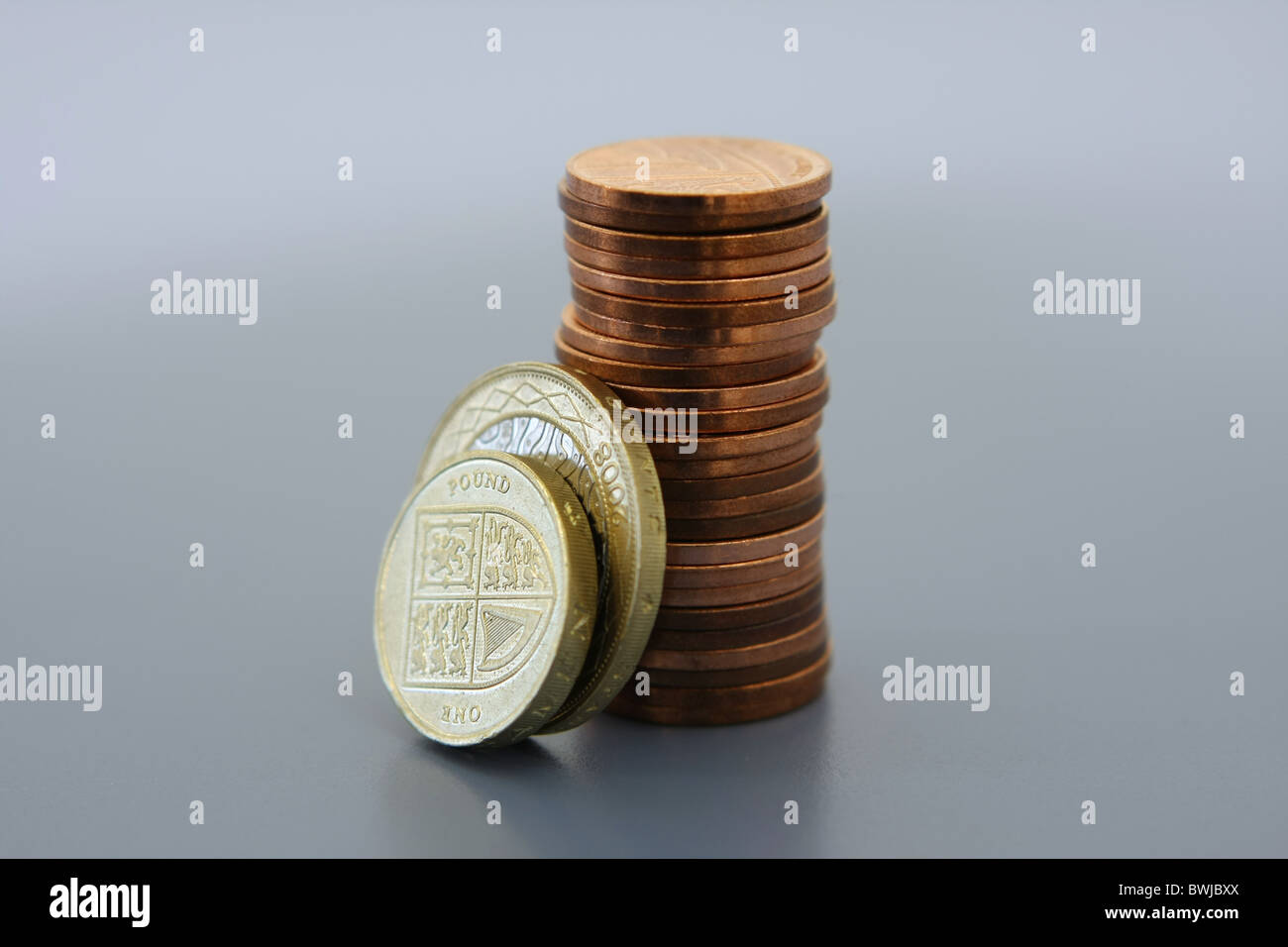 Una sterlina £2 e £1 moneta in appoggio contro una pila di 1p delle monete in euro Foto Stock