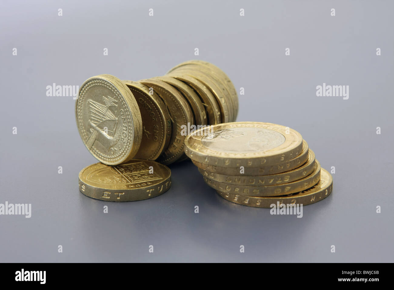 Una pila di sterling £2 monete accanto a una fila di £ 1 monete su estremità con uno in appoggio sulla parte superiore di un altro £ 1 gettone Foto Stock