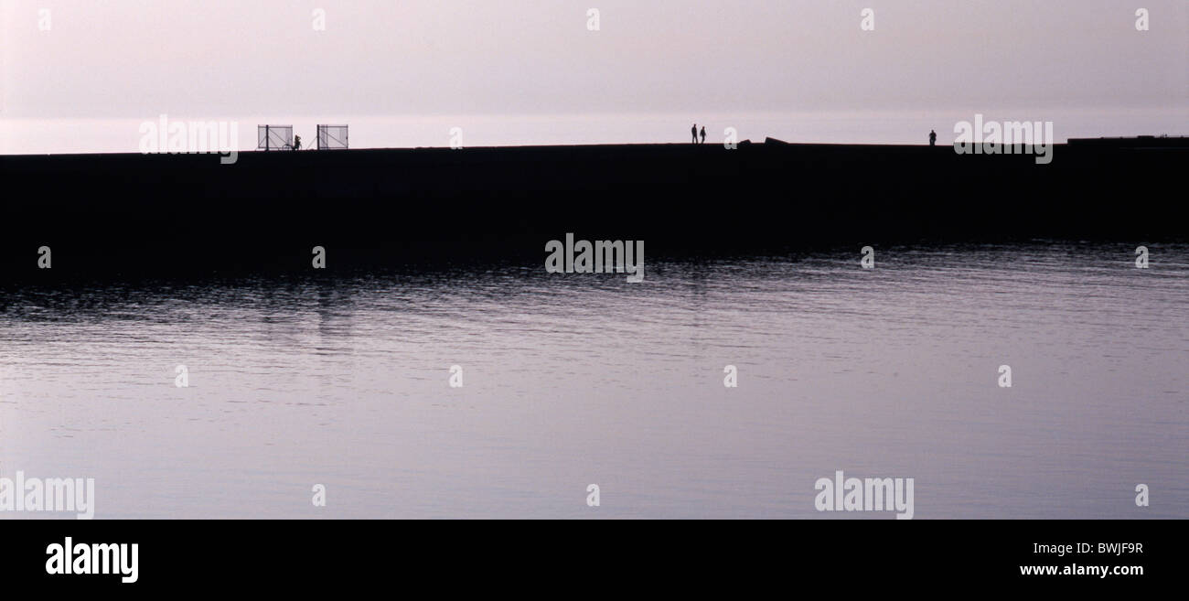 La gente che camminava nel tardo pomeriggio di sole lungo il molo del porto di Scheveningen, l'Aia, Paesi Bassi Foto Stock