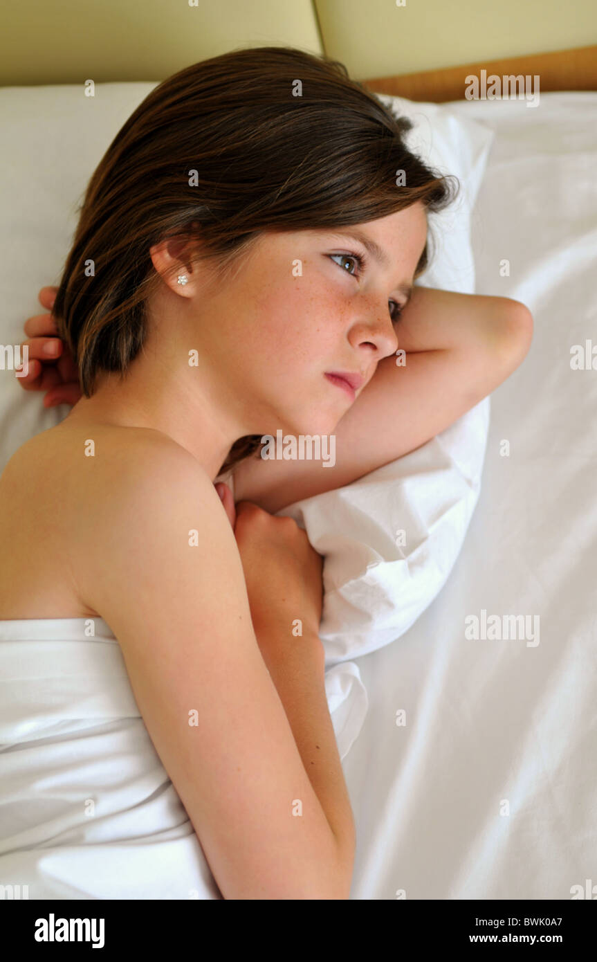 Giovane ragazza nel letto cercando premuroso o fantasticando Foto Stock