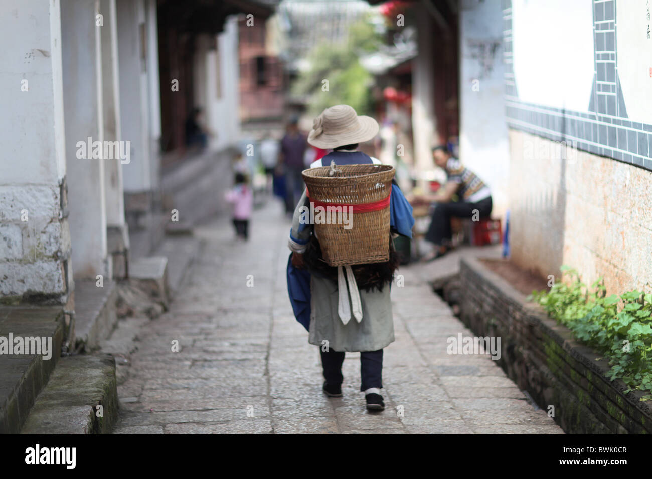 Una donna locale a piedi attraverso Lijiang Old Town, nella provincia dello Yunnan in Cina. Foto Stock