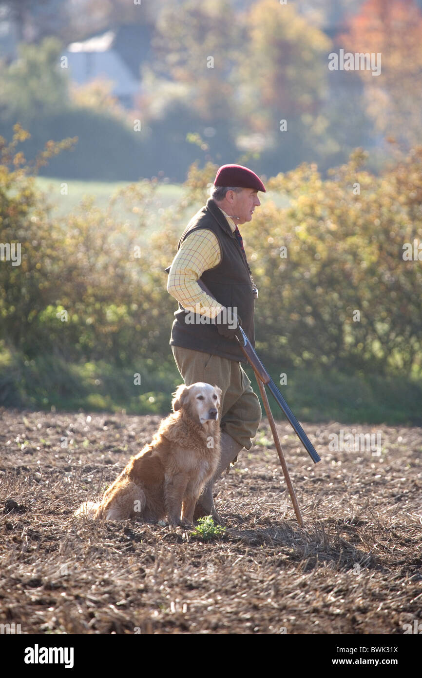 Un sparatutto (pistola) e il suo gundog attesa per la selvaggina di penna a salire su una ripresa in Cambridgeshire Regno Unito Foto Stock