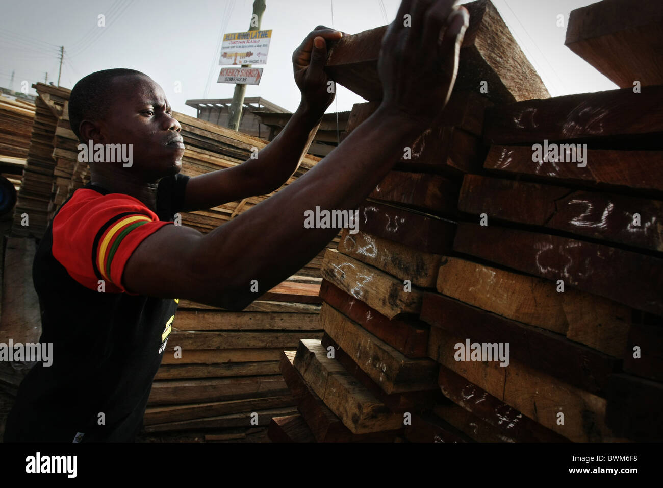 Un uomo tipi di tavole di legno per la vendita al mercato del legname in tema, Ghana il martedì 20 maggio, 2008. Foto Stock