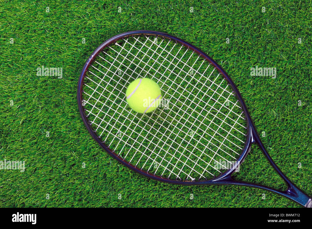 Una racchetta da tennis o la racchetta e la palla gialla sull'erba. Foto Stock