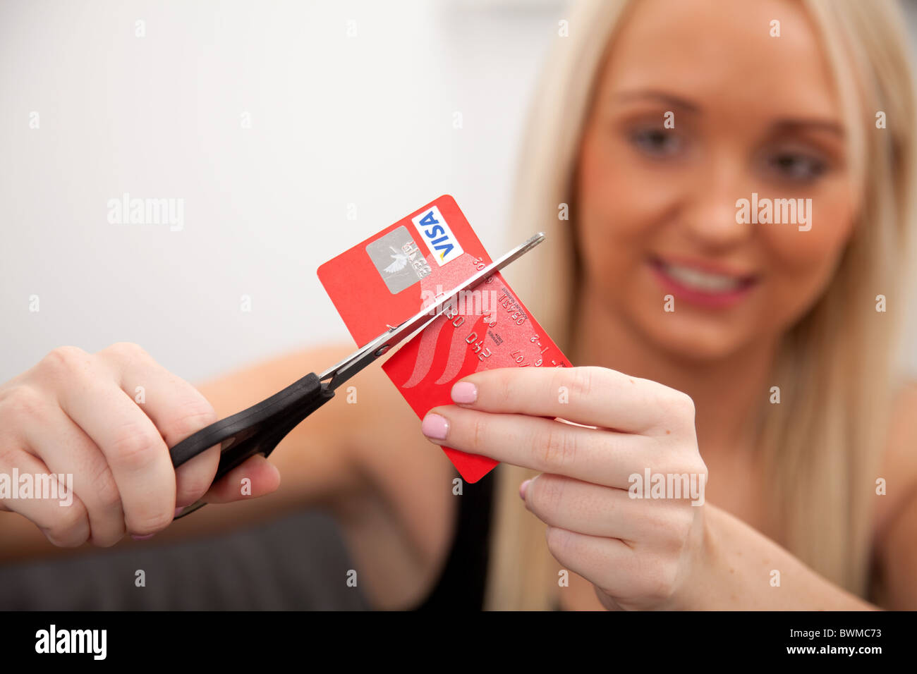 Giovane donna bionda taglio la sua carta di credito. Foto Stock