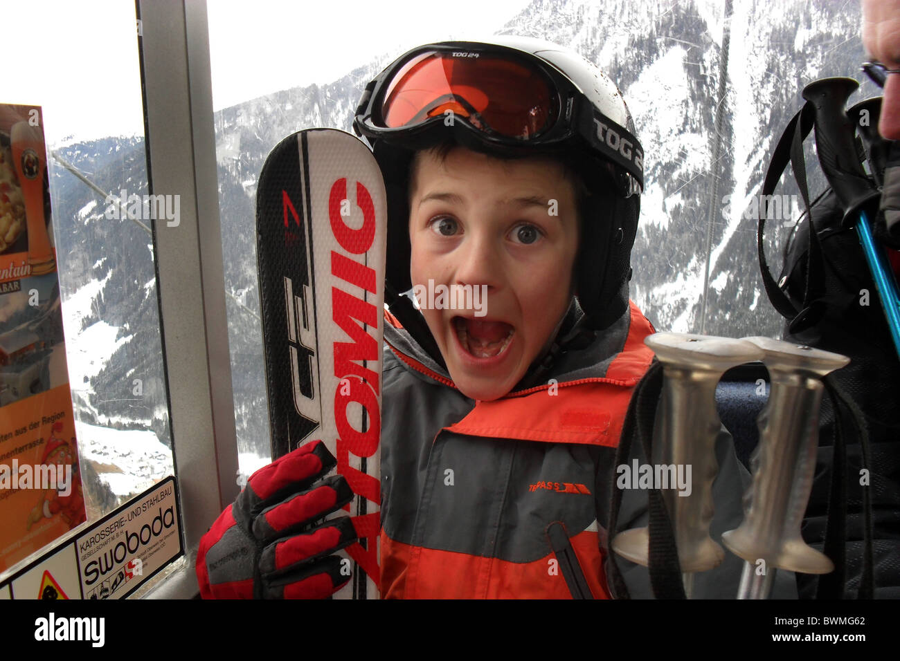 Ragazzo giovane eccitati su una vacanza sulla neve in famiglia, guardando fuori dalla seggiovia, Ischgl, Austria Foto Stock