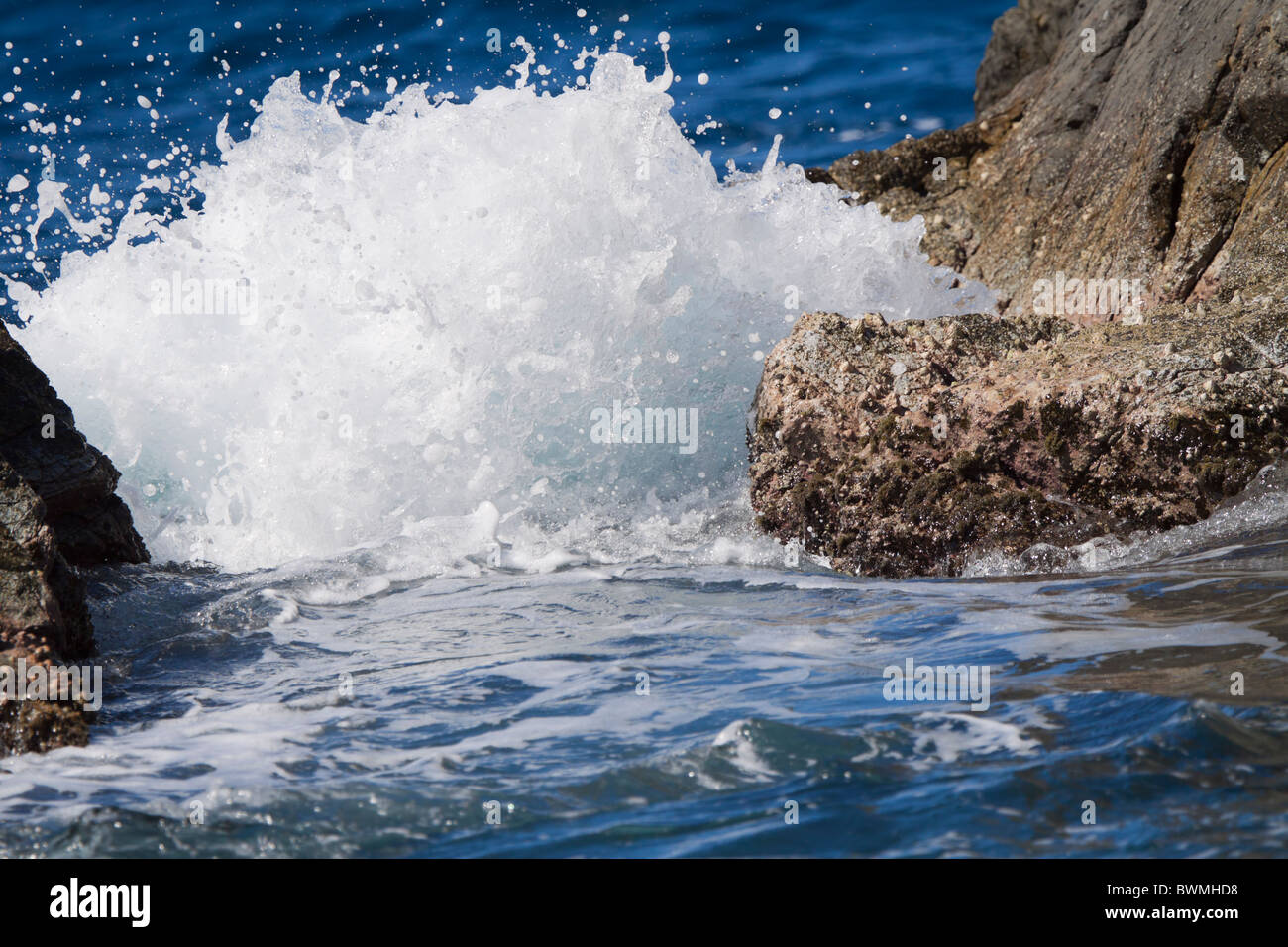 Splash. Un'onda schizzi quando colpisce un traferro stretto tra due rocce su un isola dei Caraibi Foto Stock