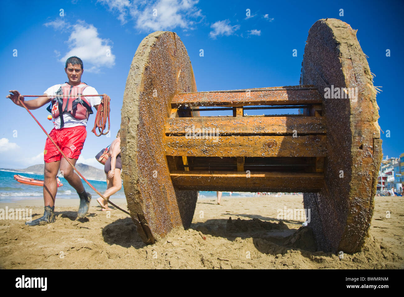 L uomo del recupero di una bobina gigante dal mare sulla spiaggia Canteras in Gran Canaria Foto Stock
