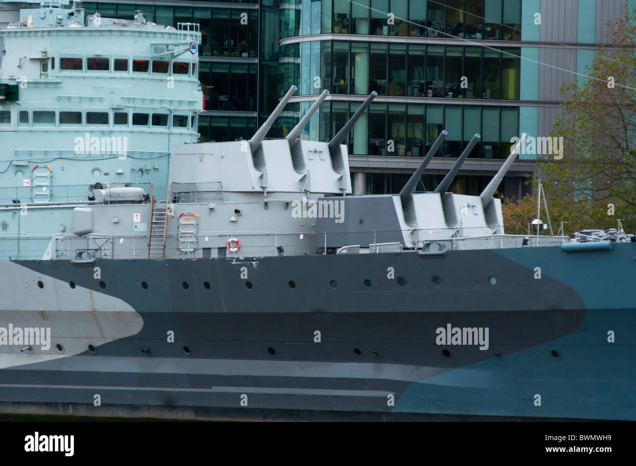 HMS Belfast pistole e uffici dietro, sul fiume Tamigi a Londra Inghilterra Foto Stock