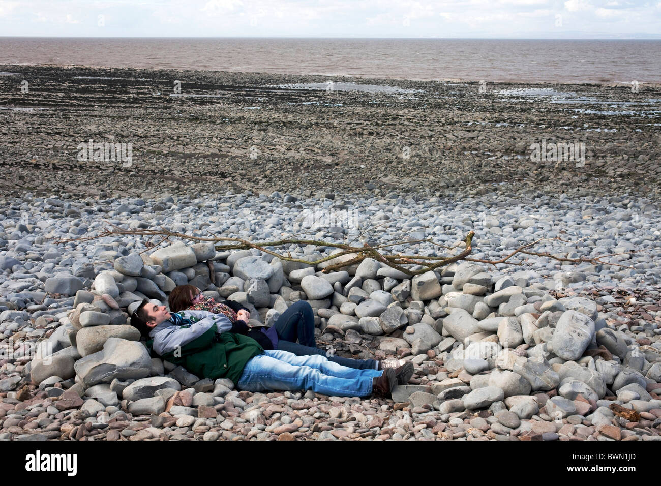Giovane sdraiato dietro le pietre per tenere fuori del vento su una passeggiata tra Lilstock a Kilve nel nord Somerset. DAVID MANSELL Foto Stock