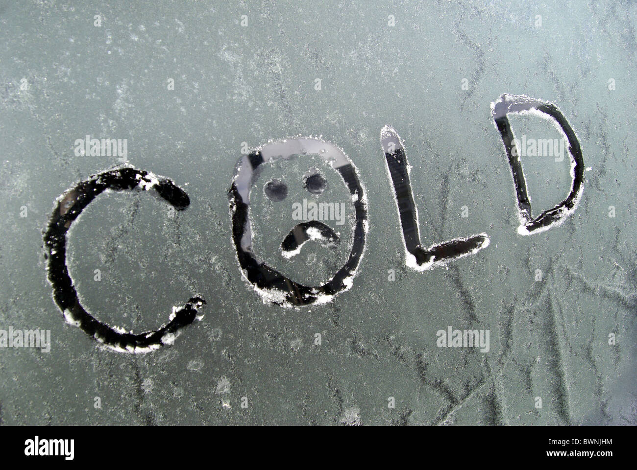La parola "COLD" scritte su frost/smerigliato finestra auto . Dotato di una faccina triste tracciata nella lettera 'O'. Raffigurante il ghiaccio di congelamento Foto Stock