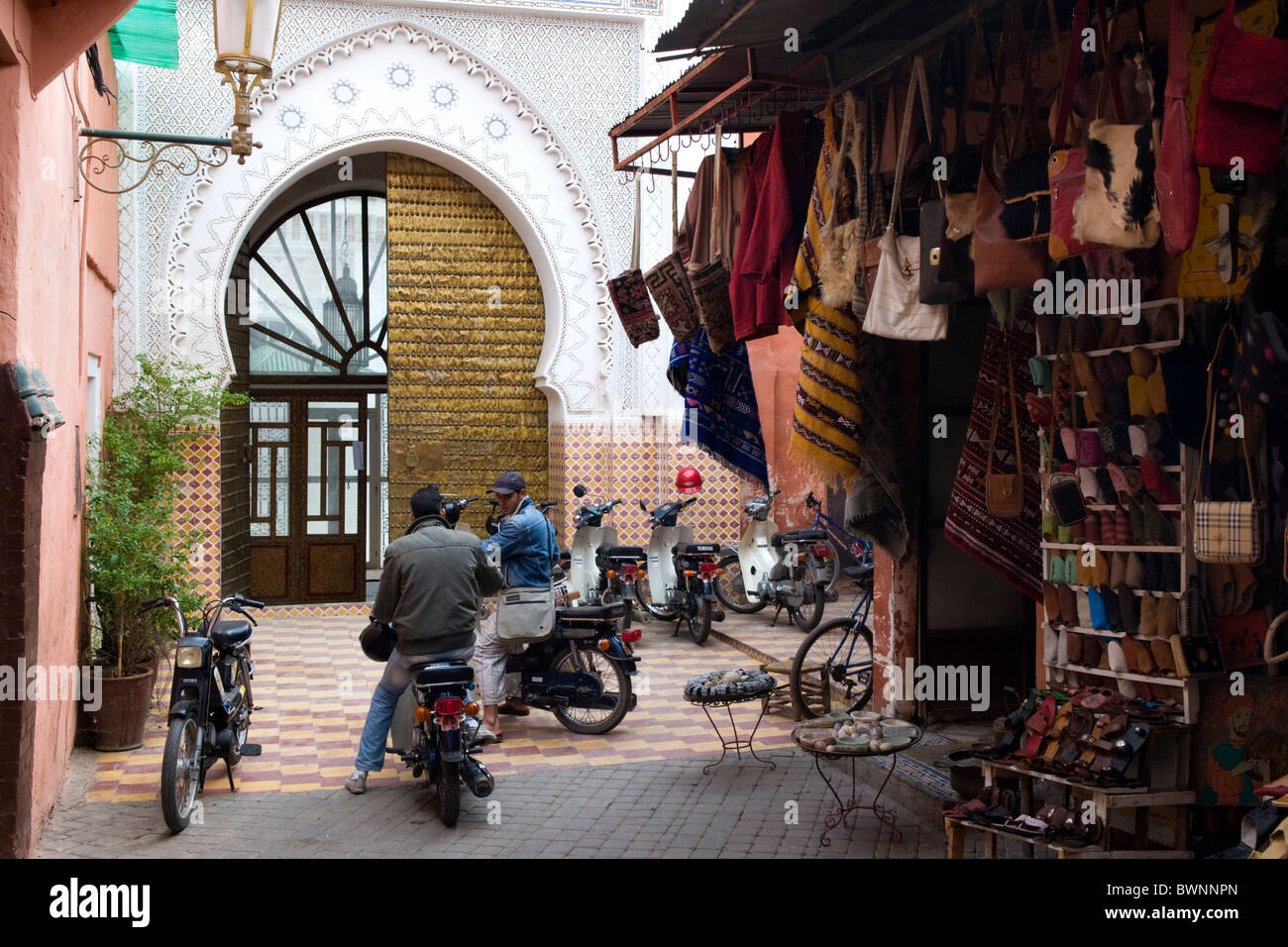 Giovani uomini sul ciclomotore in un Souk accanto a un lussuoso Riad di Marrakech Africa del Nord Foto Stock