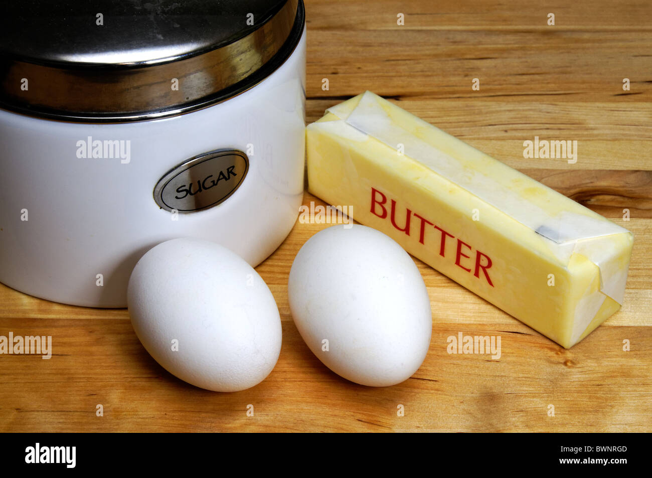 Barattolo di zucchero, due uova e stick di burro. Foto Stock