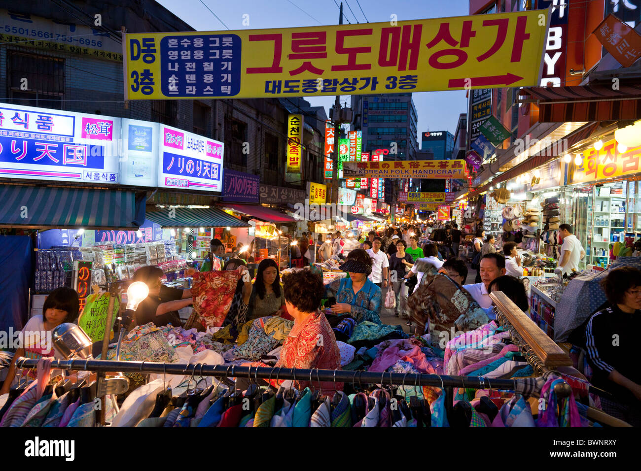 I coreani shopping in stallo la vendita di abbigliamento in al mercato di Namdaemun a Seoul Corea del Sud al tramonto. JMH3857 Foto Stock