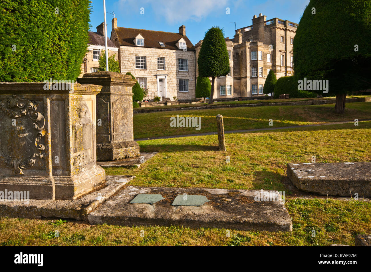St Mary's sagrato con yew alberi e Cotswold cottage in pietra in background, Painswick, Gloucestershire, Regno Unito Foto Stock