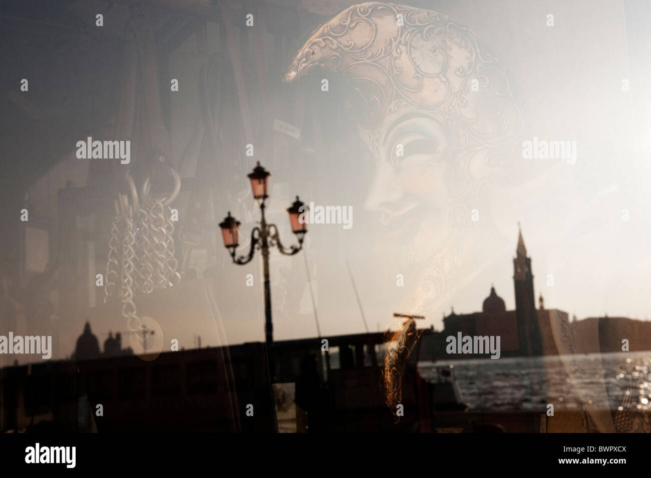 Una maschera in un negozio a Venezia con San Giorgio Maggiore riflessa nella finestra . Foto Stock