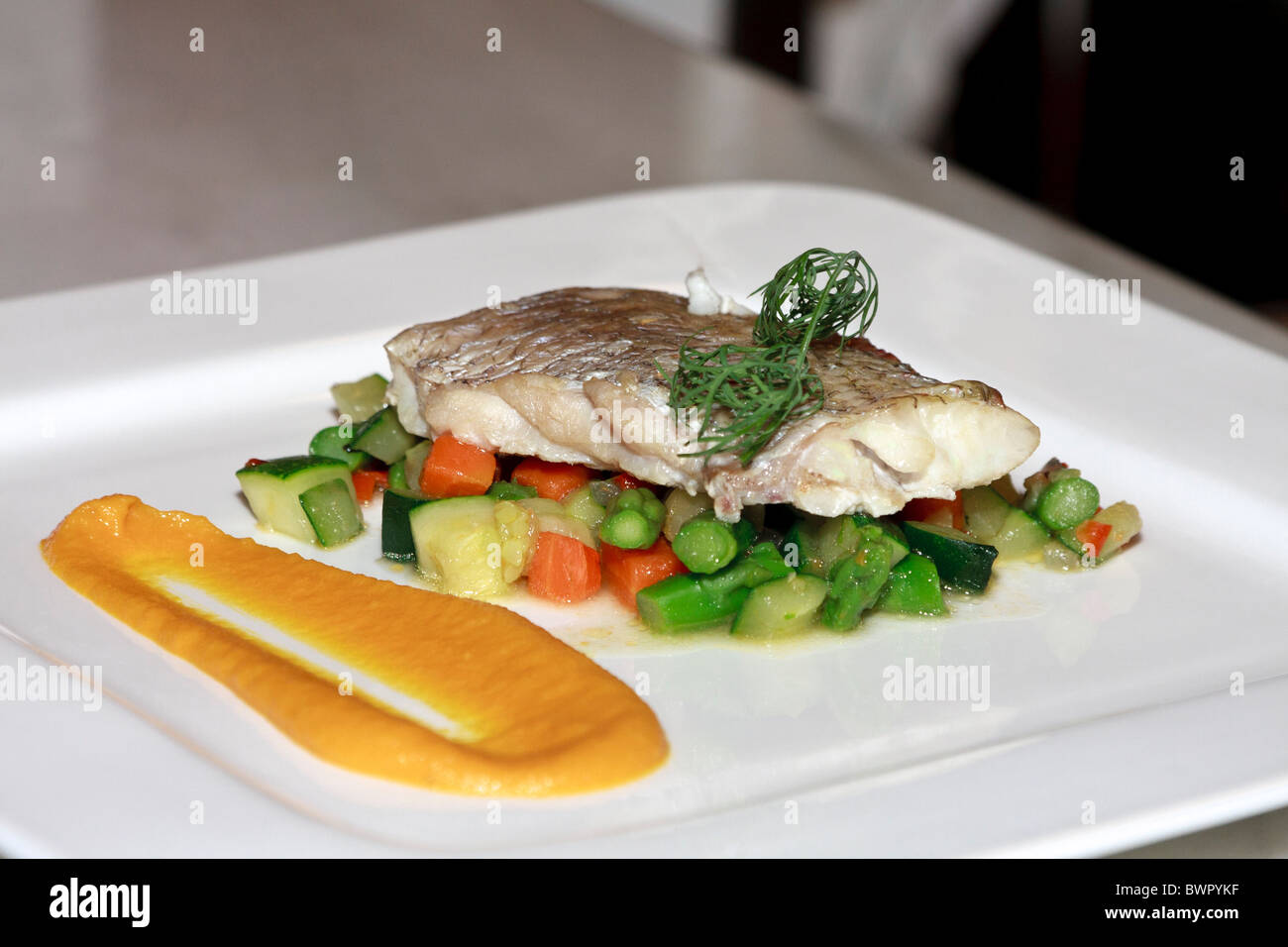 Un filetto di pesce su un letto di verdure pronte per essere servite in un ristorante Foto Stock