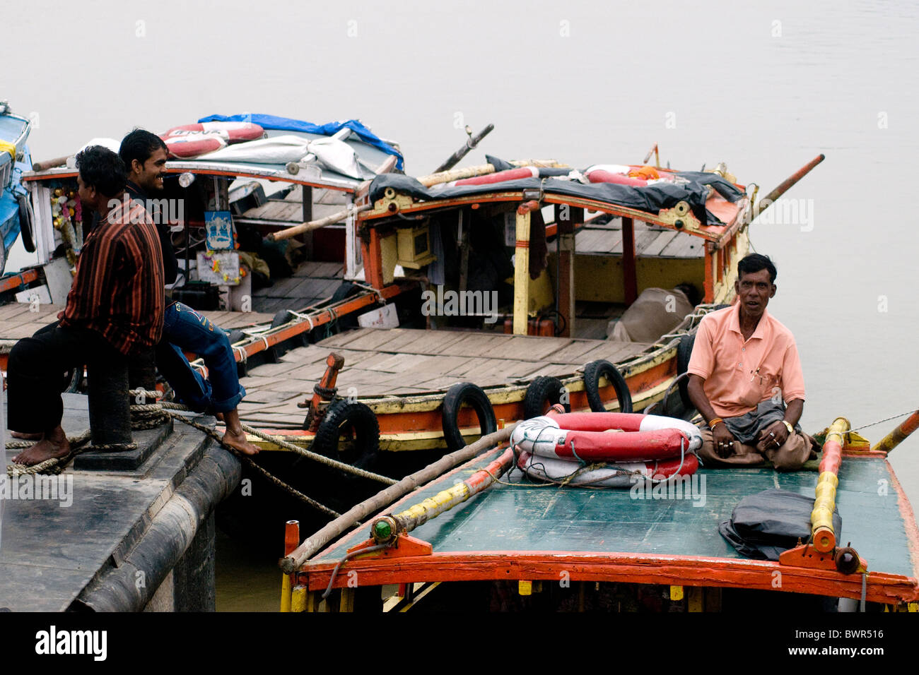 Un barcaiolo rilassa sulla cima di una nave traghetto sul Fiume Hooghly su quella di Howrah shore vicino a Kolkata Foto Stock