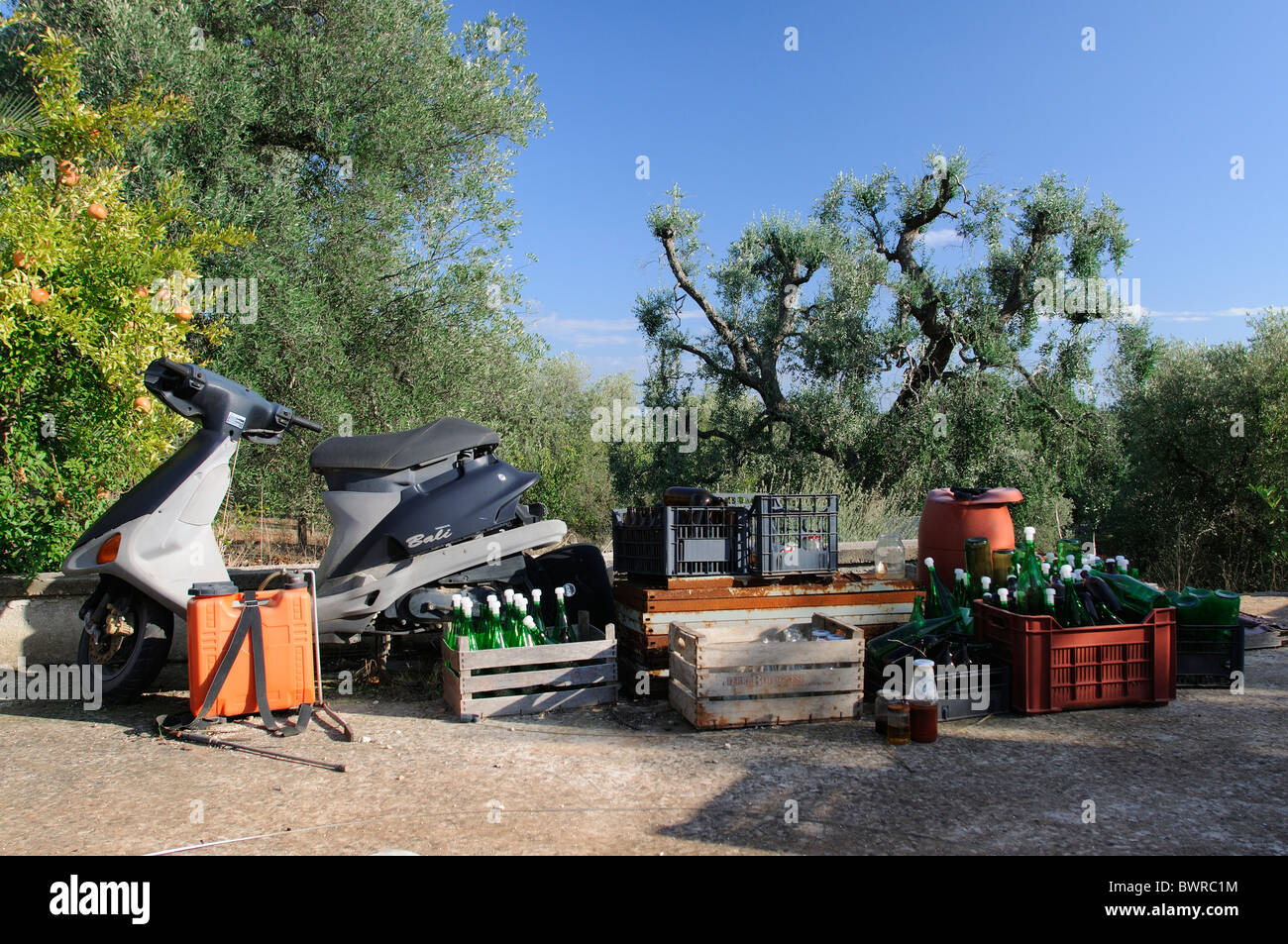 Scooter con bottiglie e un assortimento di posta indesiderata su giardino vialetto in Italia Foto Stock