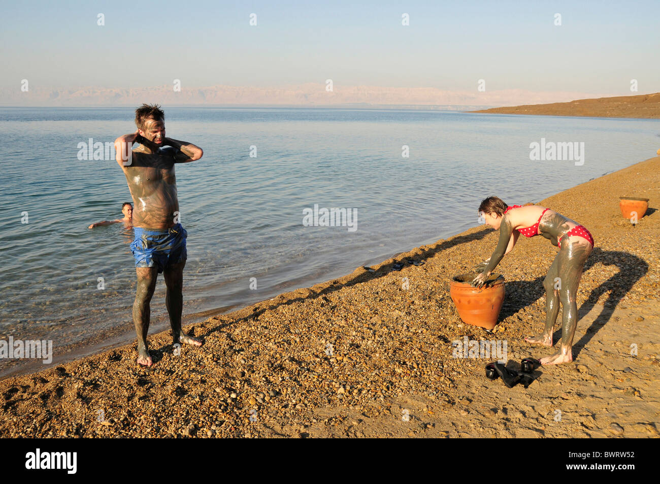 I turisti cosparse con il salato il fango del Mar Morto, vicino Suwaymah, Giordania, Medio Oriente, Orient Foto Stock