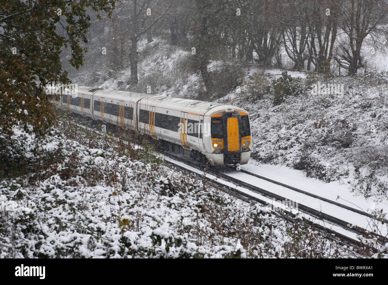 Un treno correre attraverso il Kent innevato paesaggio invernale Foto Stock