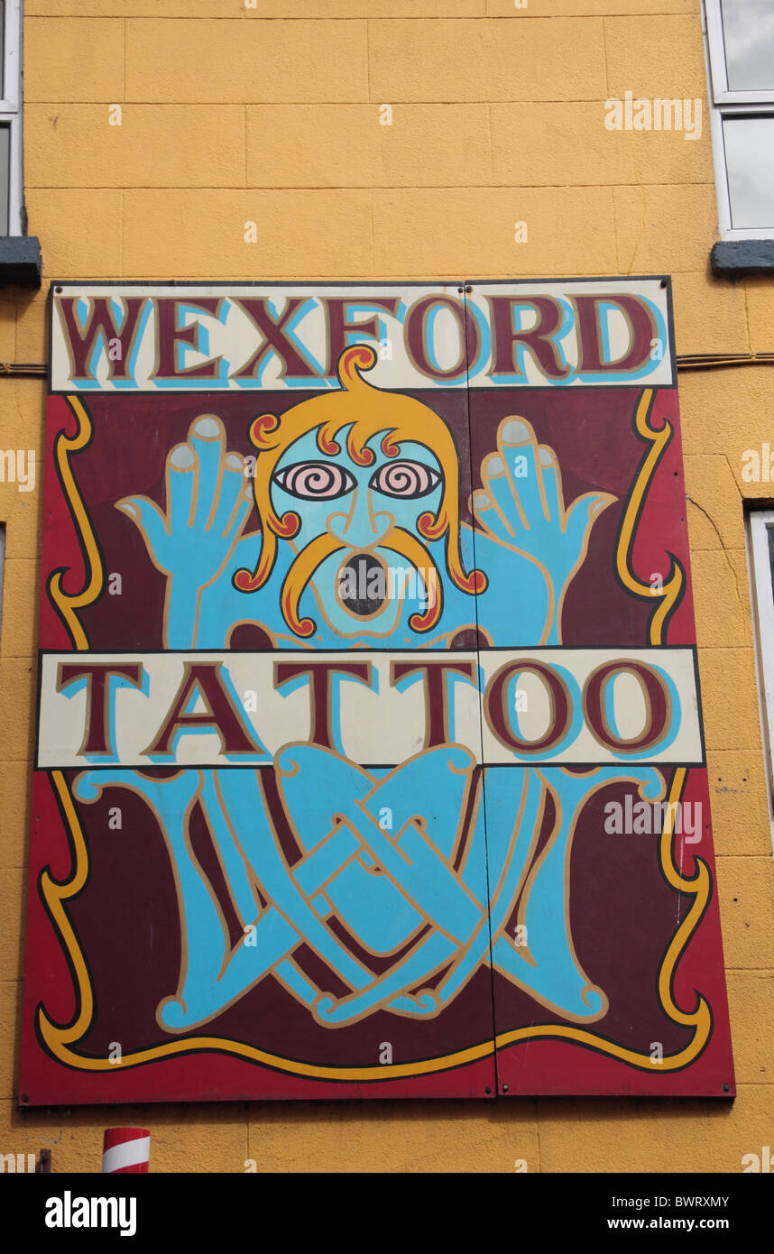 Un grande dipinto di segno pubblicità Wexford salotto tattoo e la cittadina di Wexford, Co. Wexford, Irlanda (Eire). Foto Stock