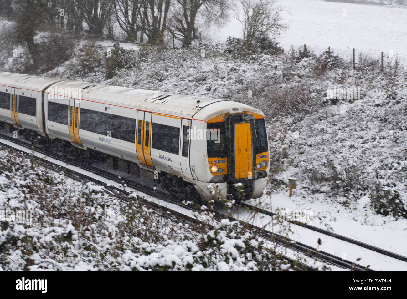 Un treno correre attraverso il Kent innevato paesaggio invernale Foto Stock