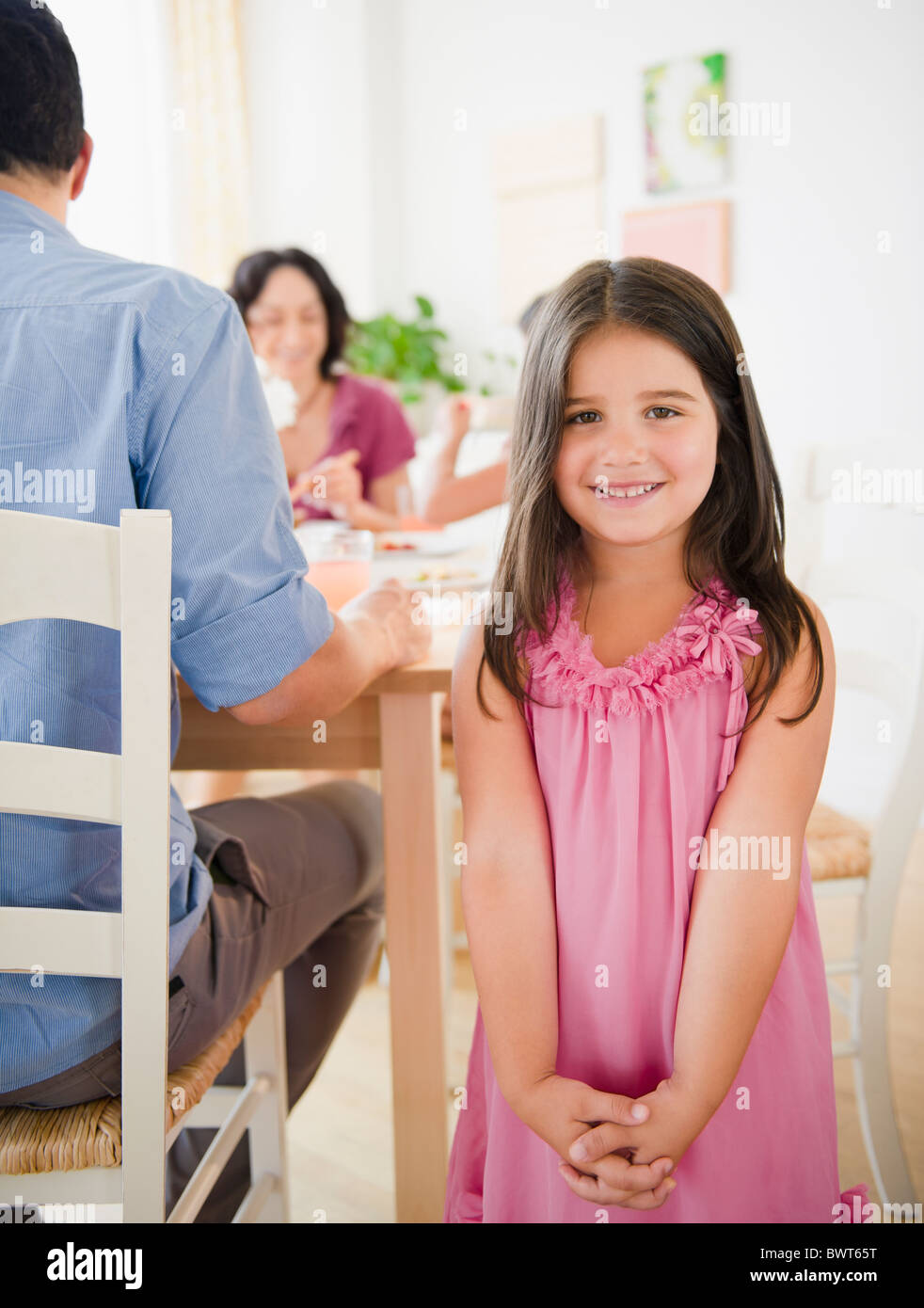 Ragazza sorridente con la famiglia a tavola di cena dietro di lei Foto Stock