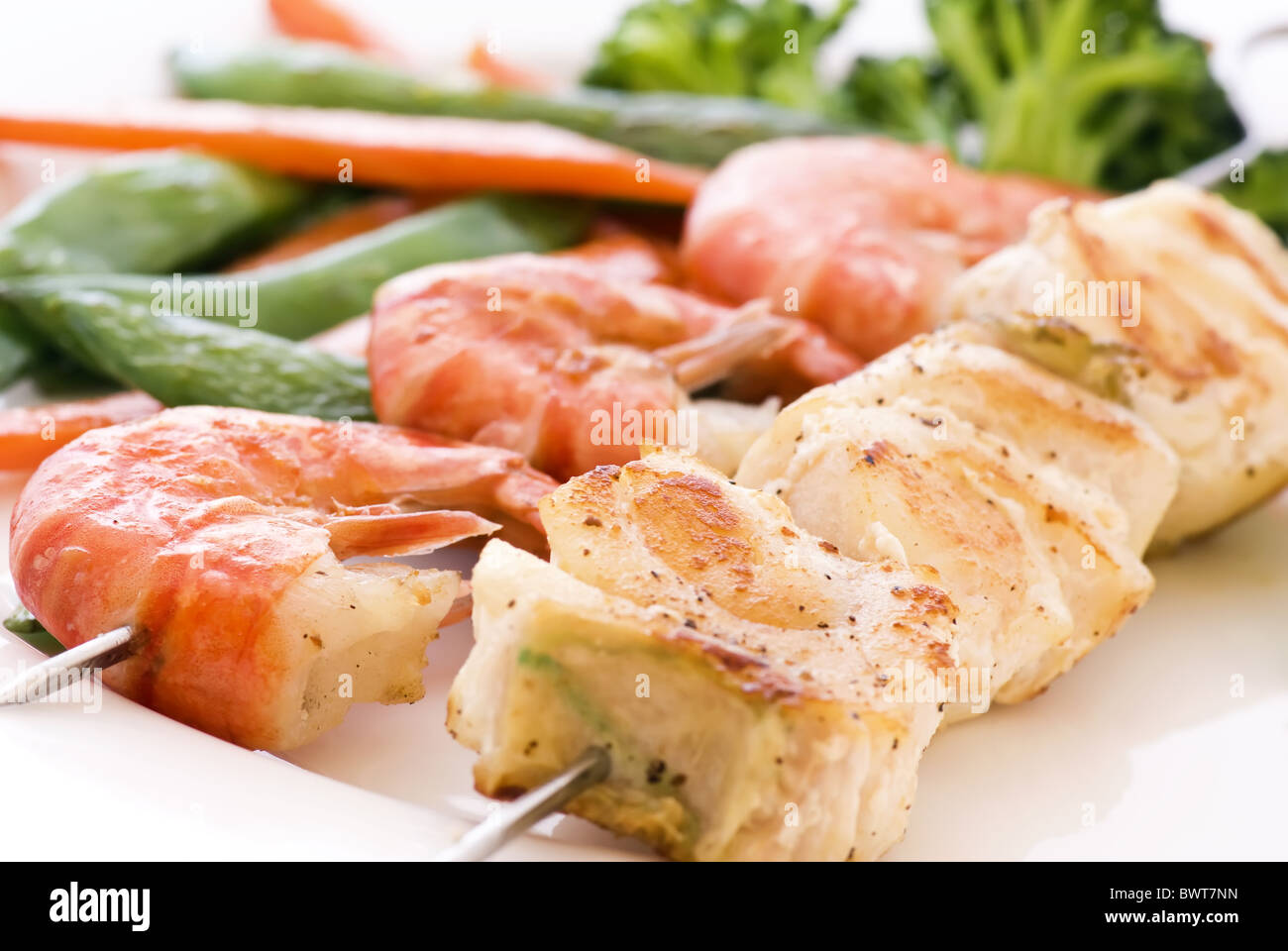 Red snapper e gamberetti su spiedino di verdure come primo piano su una piastra bianca Foto Stock