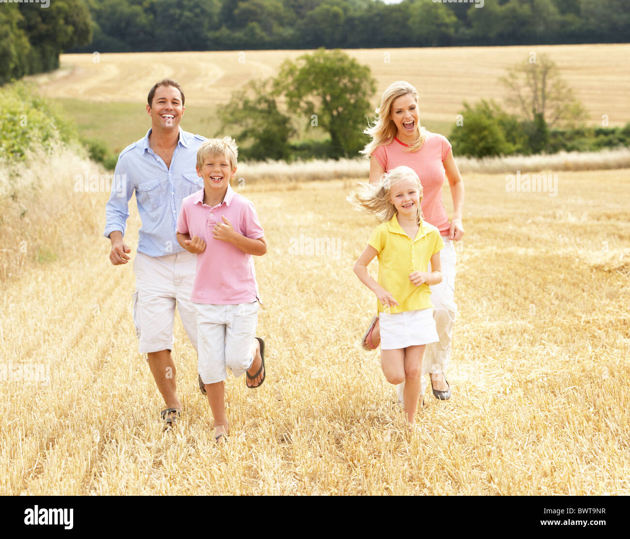 Famiglia correndo insieme attraverso Estate Campo di raccolto Foto Stock