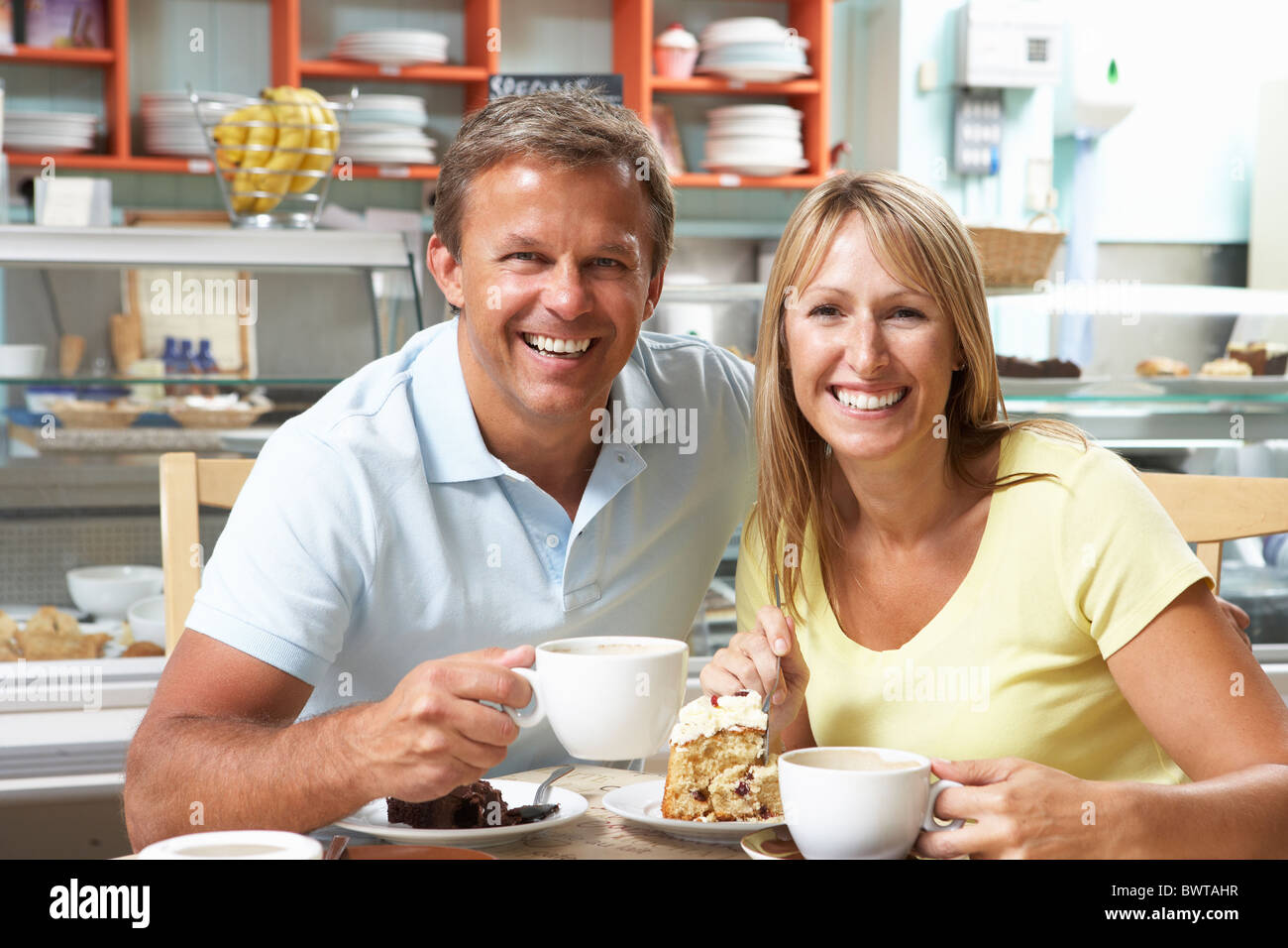 Giovane godendo di fetta di torta e caffè nella caffetteria Foto Stock