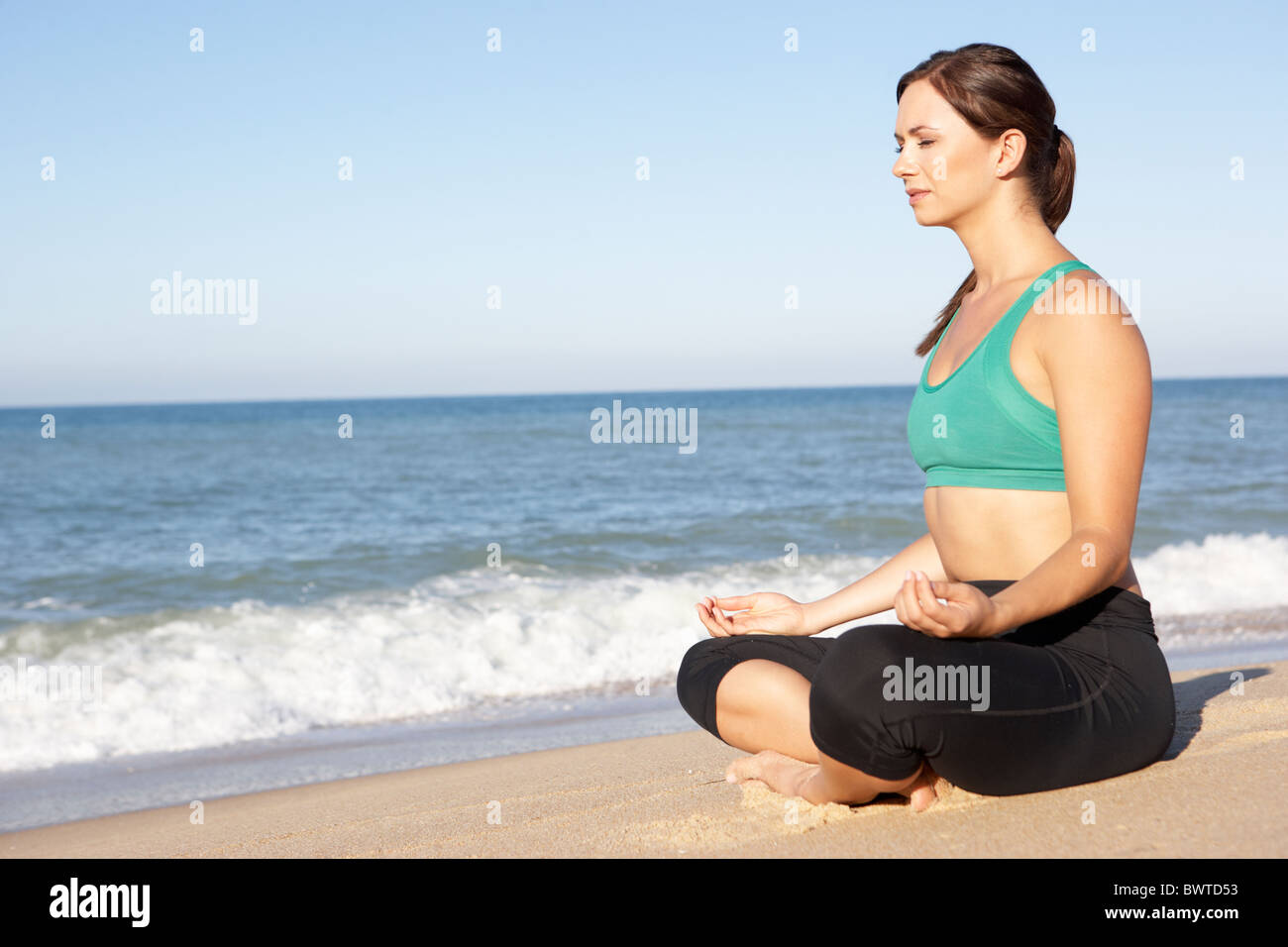 Giovane Donna Abbigliamento Fitness meditando sulla spiaggia Foto Stock