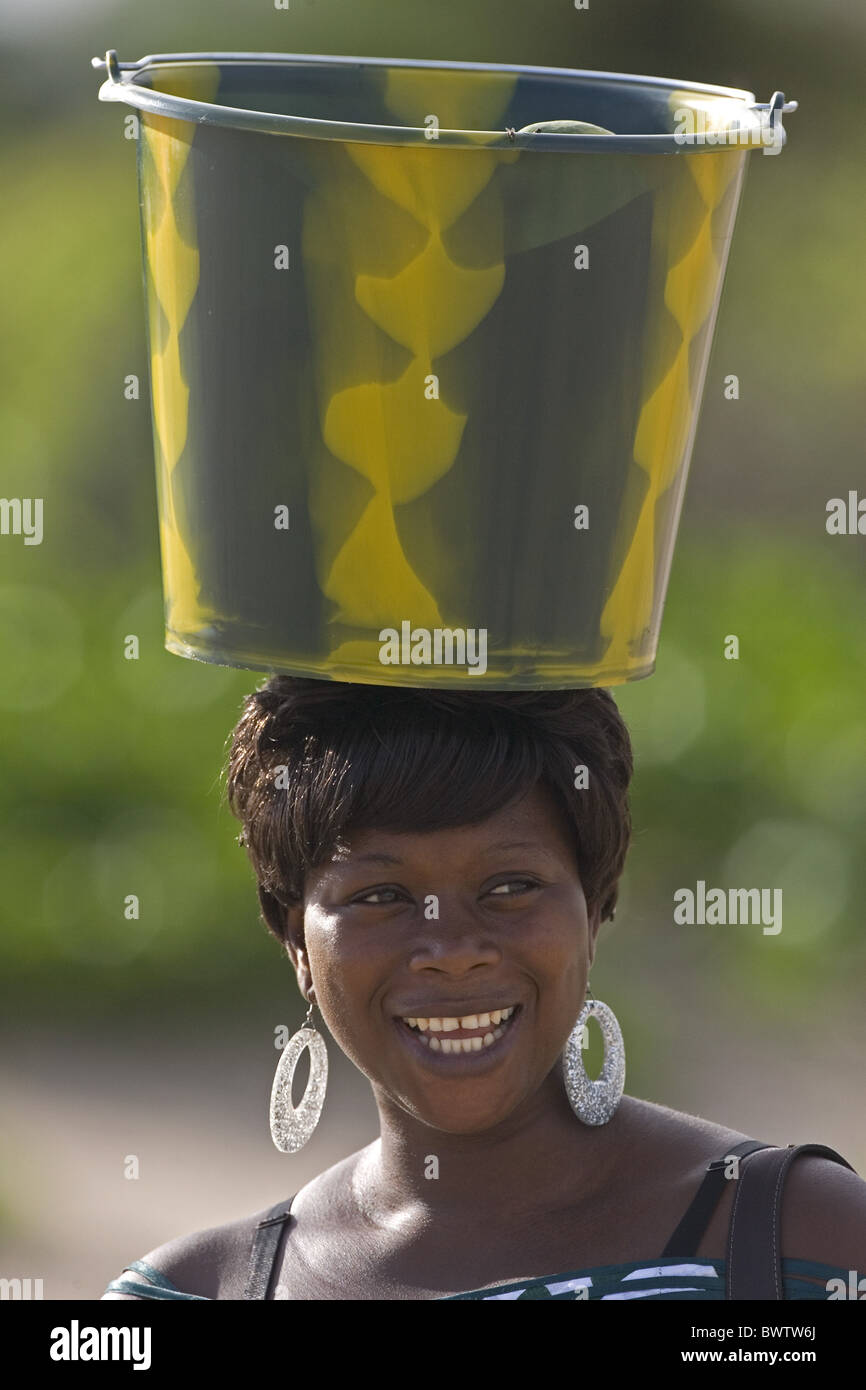 Donna sorridente con benna equilibrato sul capo il Senegal Foto Stock