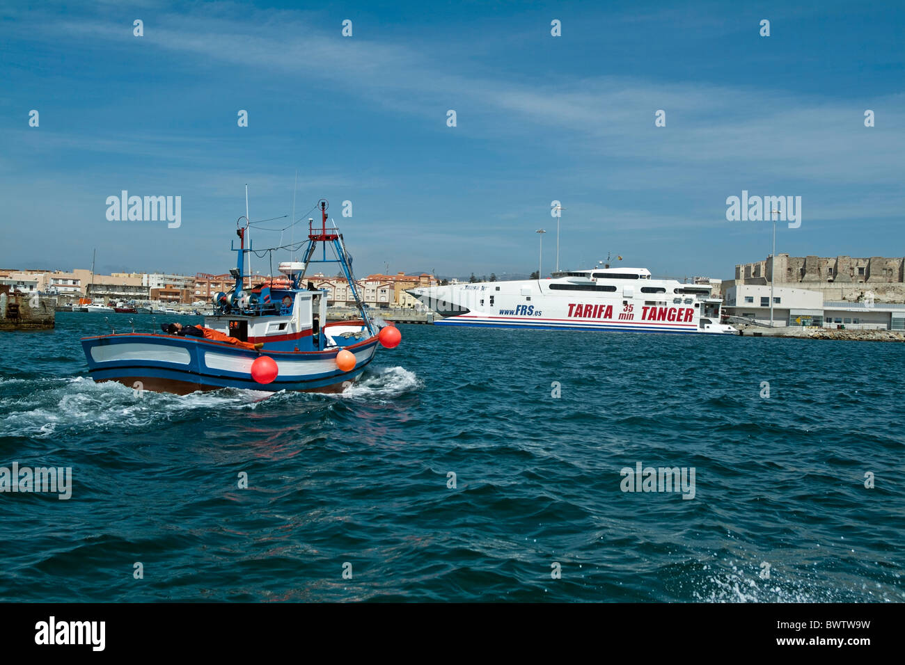 Persona sdraiata sulla schiena di una barca da pesca come esso ritorna al porto di Tarifa, Andalusia, Spagna. Foto Stock