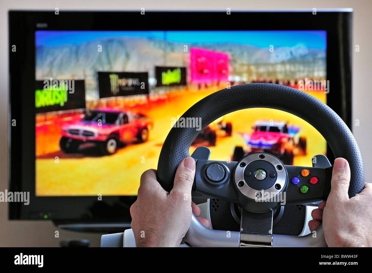 Volante controller nella parte anteriore dello schermo del televisore che mostra le vetture nel gioco di corse Foto Stock