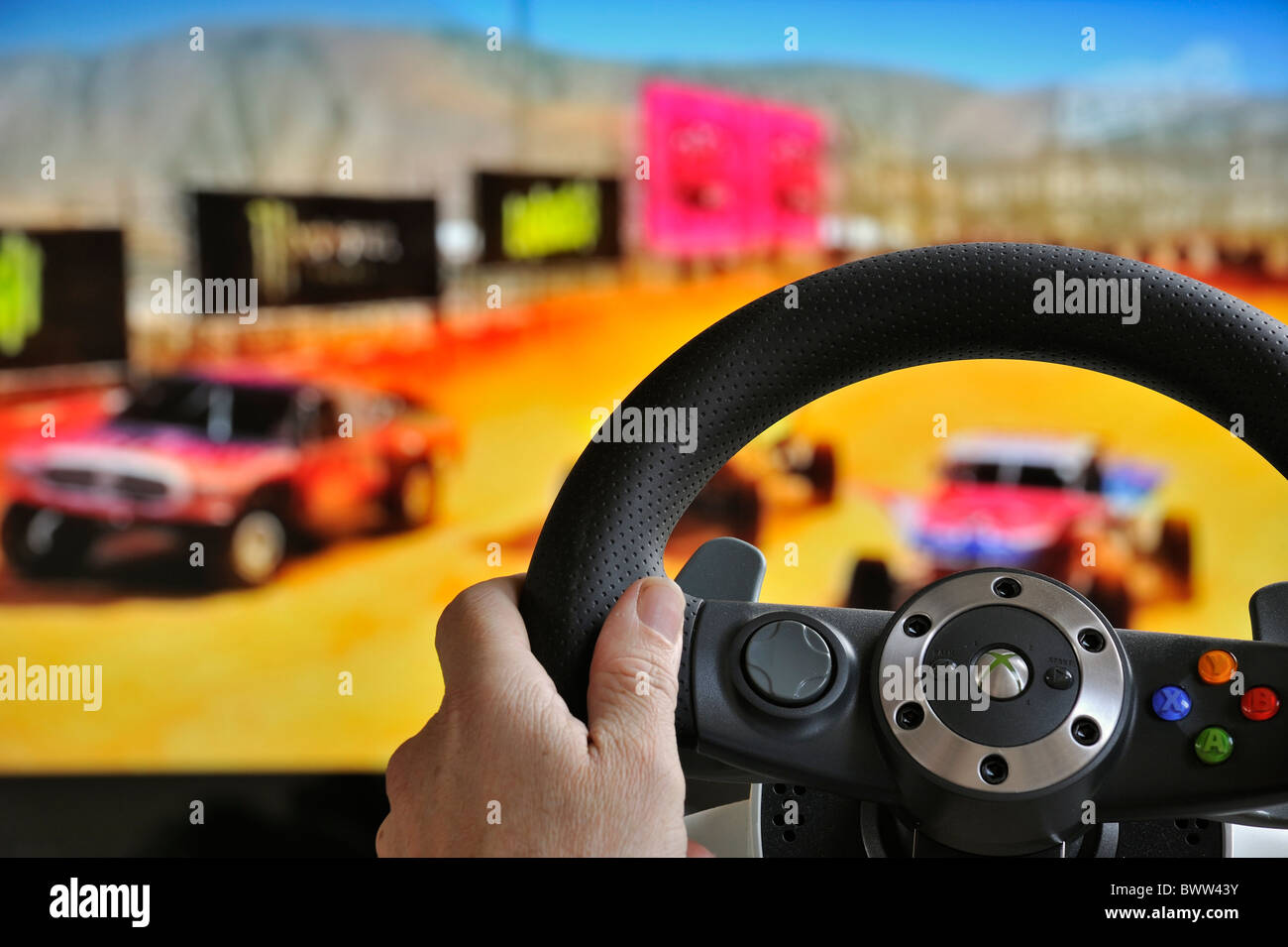 Volante controller nella parte anteriore dello schermo del televisore che mostra le vetture nel gioco di corse Foto Stock