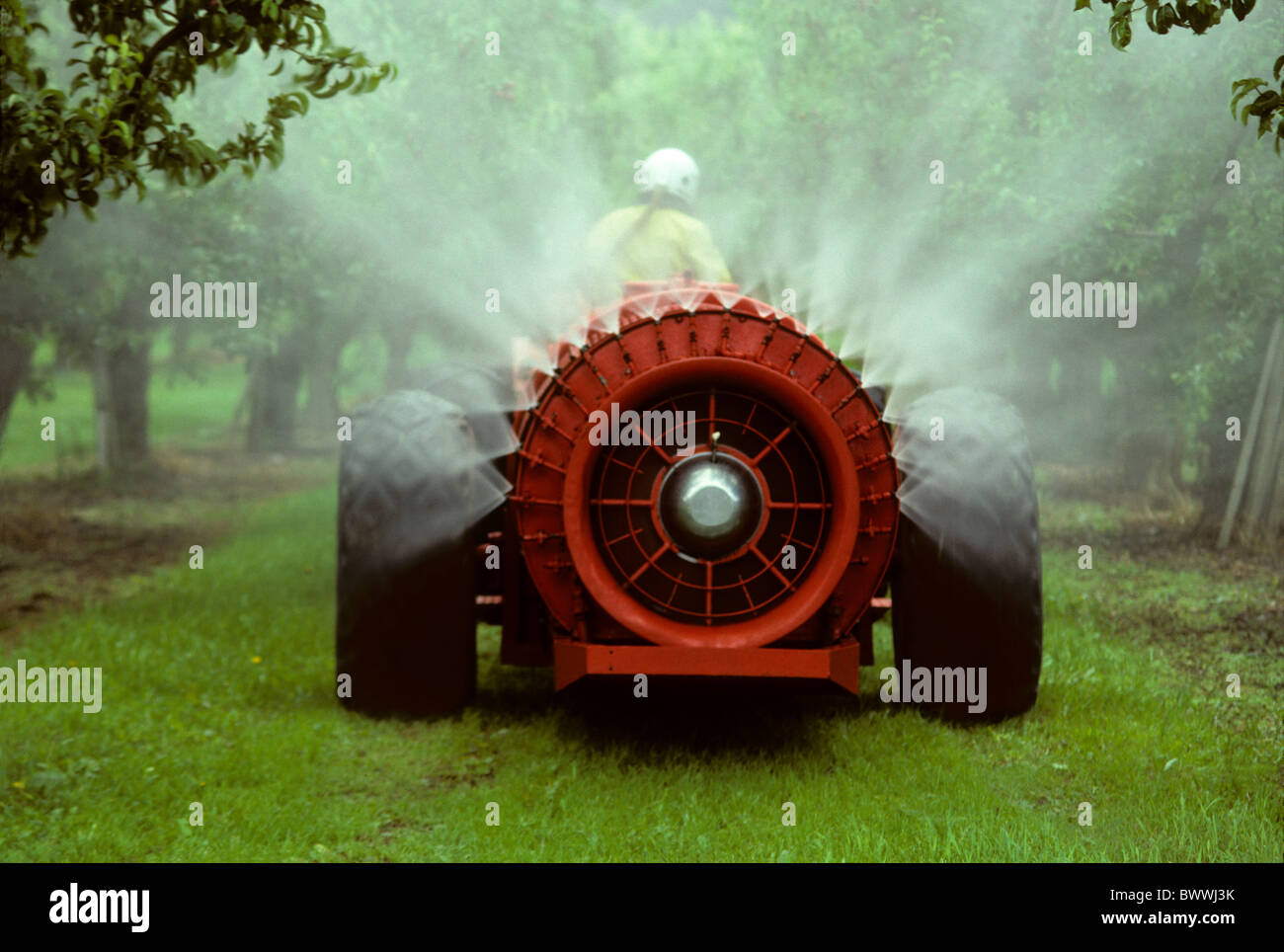 Irroratrice rosso la spruzzatura di un Apple Orchard Foto Stock