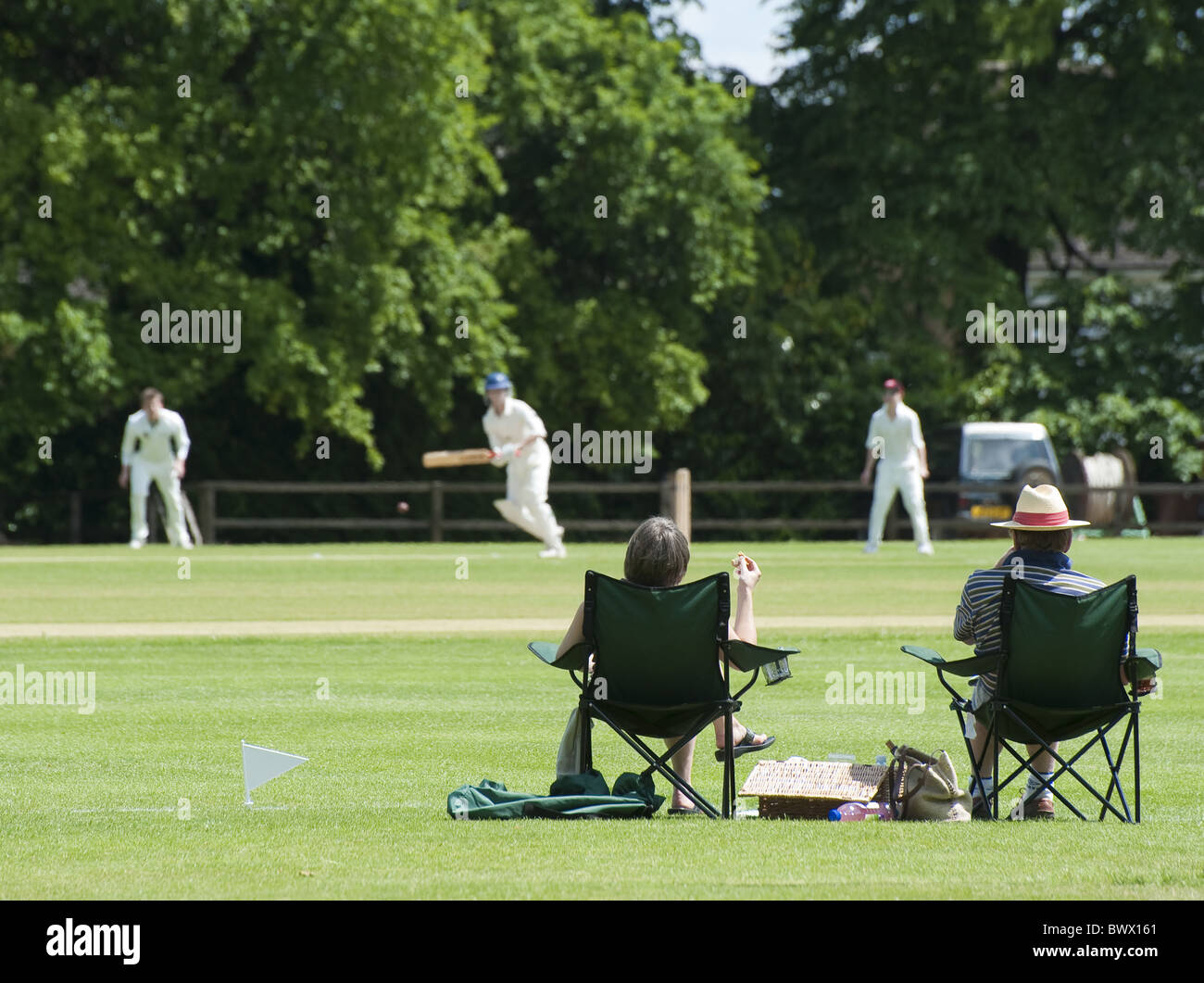 Due spettatori villaggio guardare la partita di cricket Foto Stock