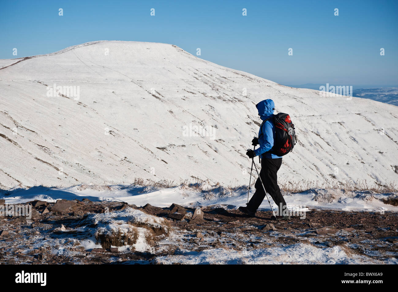 Escursionista femmina in inverno con Pen Y Fan in background, Parco Nazionale di Brecon Beacons, Galles Foto Stock