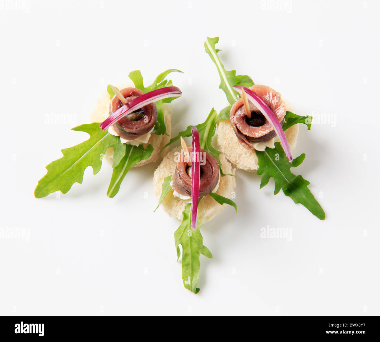 Crostini di acciuga guarnite con foglie di rucola e cipolla Foto Stock
