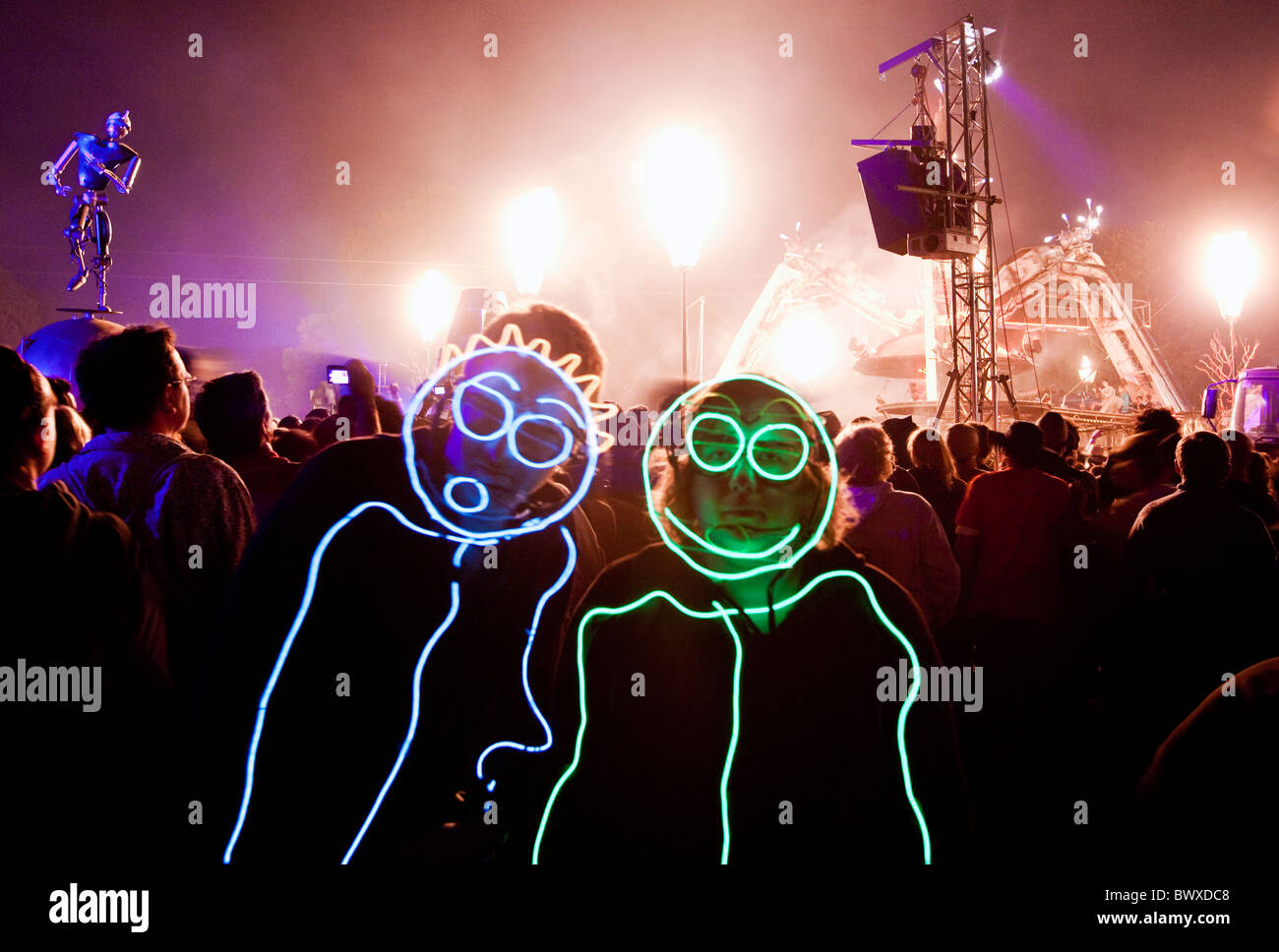 I frequentatori del festival in tute luminoso vicino a Arcadia festival di Glastonbury Somerset REGNO UNITO Europa Foto Stock