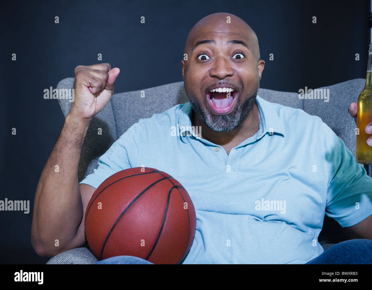 African American uomo a bere birra e guardare la pallacanestro in televisione Foto Stock