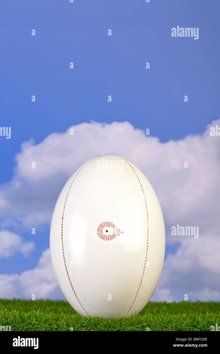 Foto di un pallone da rugby tee'd fino a erba con lo sfondo del cielo. Foto Stock
