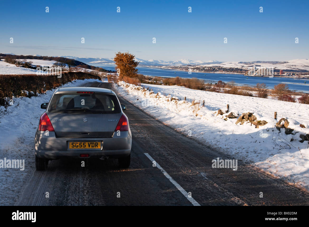 Auto su una coperta di neve strada rurale in inverno, Renfrewshire, Scozia Foto Stock