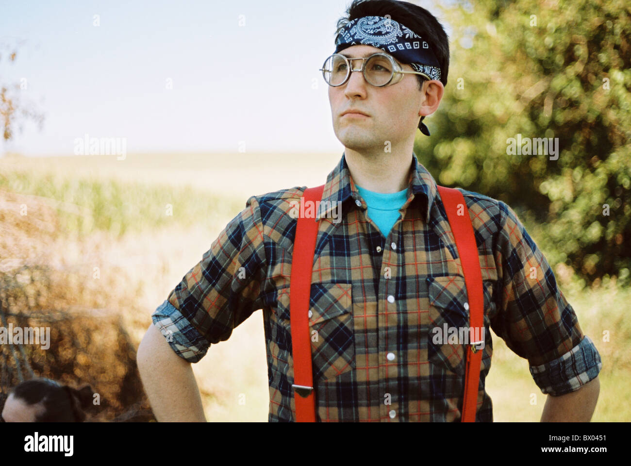 Un uomo che indossa gli occhiali bombardiere, una bandana, di flanella, e bretelle. Foto Stock